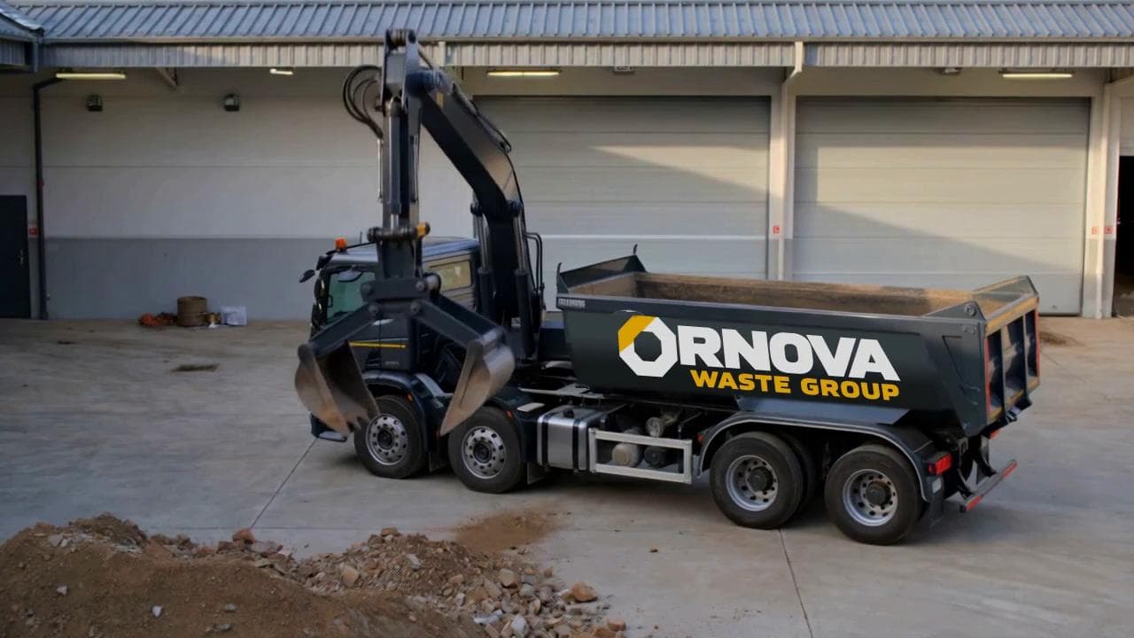 Illustrative Ornova grab lorry scooping and loading rubble into its rear body.