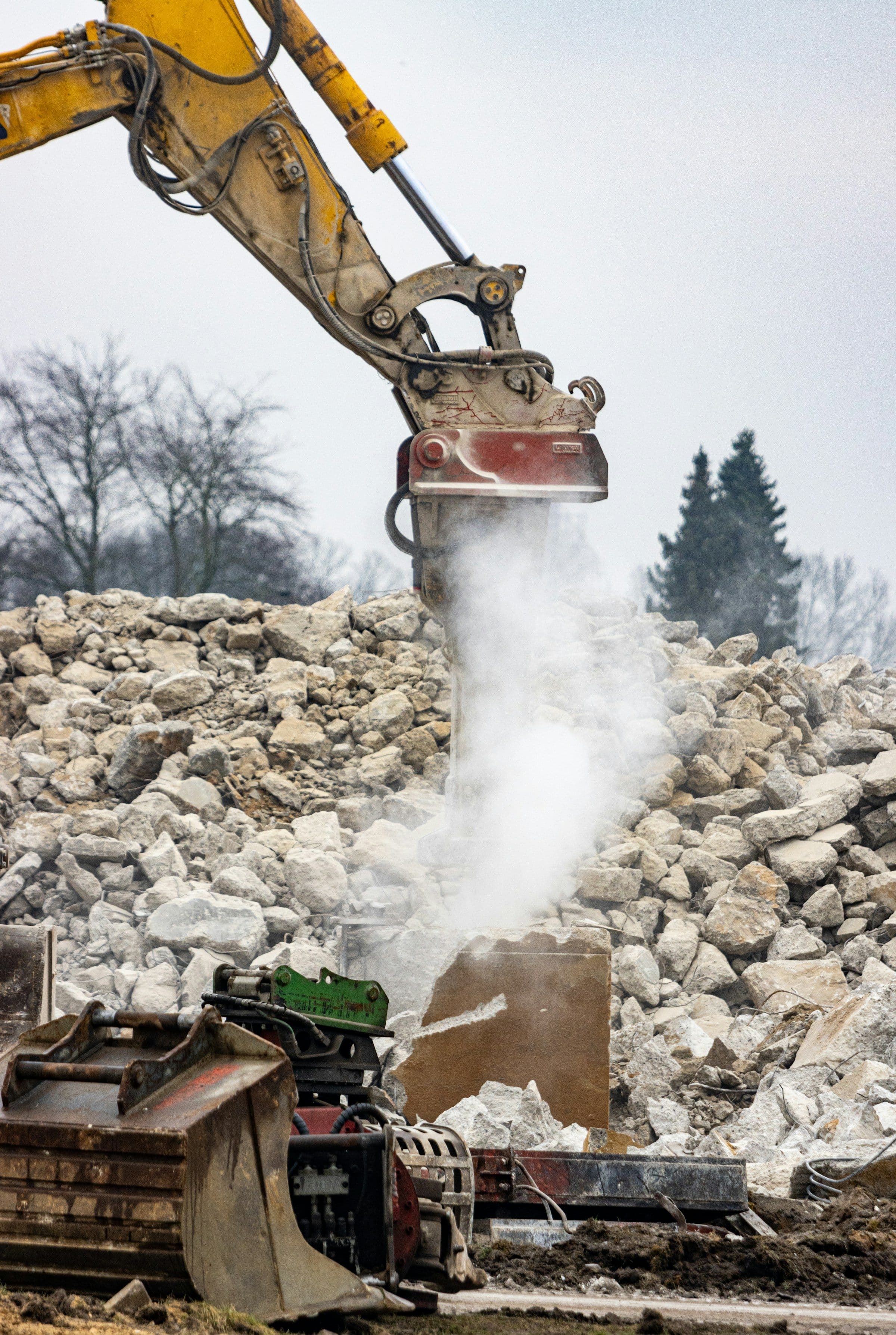 Dust rising as an excavator breaks up a pile of rubble